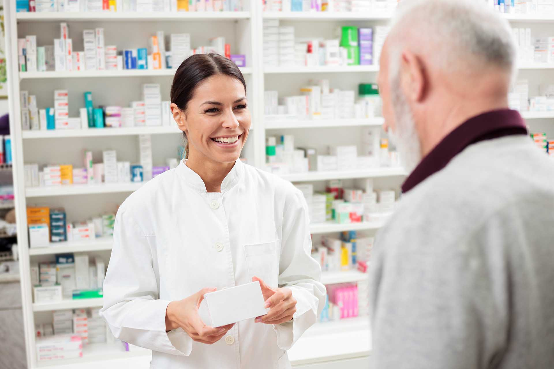 Se veria una mujer en un mostrador de una farmacia atendiendo.